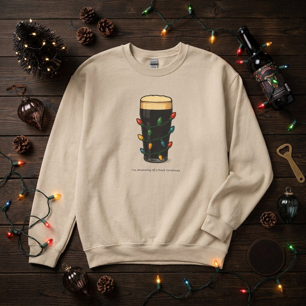 A beige crewneck sweatshirt laid flat on a dark wood surface, decorated with holiday lights, pinecones, ornaments, and a bottle. The sweatshirt features a graphic of a pint of dark beer wrapped in colorful Christmas lights with the text 'I'm drinking to forget troubles' underneath.