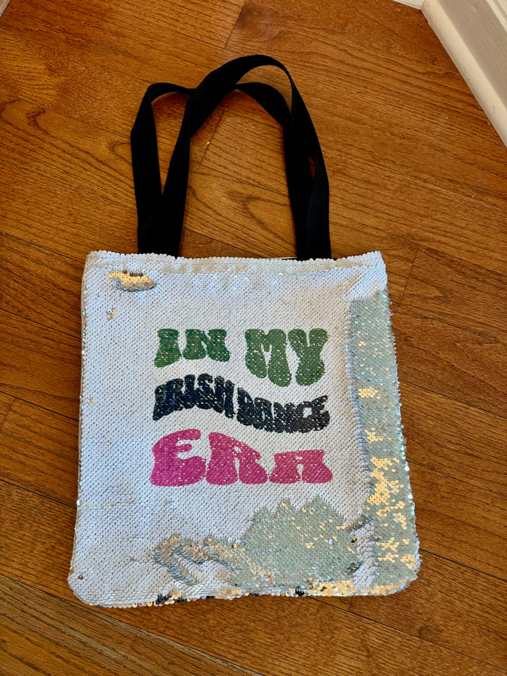 In my Irish Dance Era Sequin ToteGet ready to dance the day away with our In my Irish Dance Era Sequin Tote! This 14" by 14" tote features a white sequin front with our original design and a plain canvas back that can be personalized with your name in bla