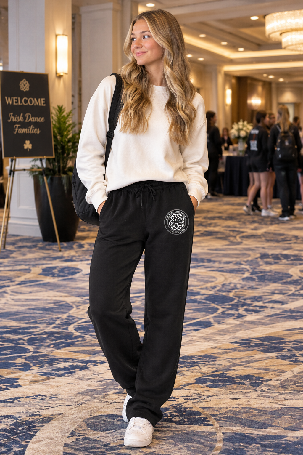 Dancer wearing West Coast Academy black sweatpants with the white crest logo at an Irish dance event