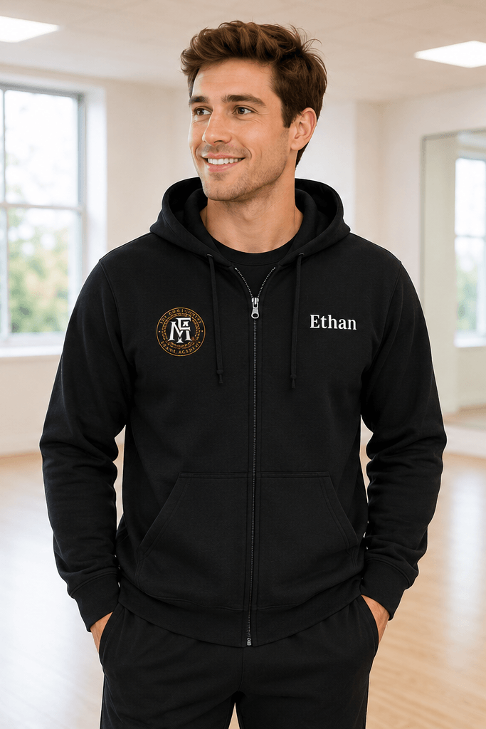 A man modeling a black zip-up hoodie in a bright indoor studio, shown from both the front and back. The front has a small circular crest on the left chest and the name 'Ethan' on the right chest.