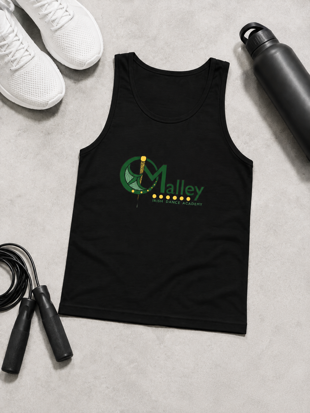 A black sleeveless tank top laid flat on a light gray surface, featuring a green and yellow 'OMalley' graphic on the chest. White sneakers, a black water bottle, and a jump rope are arranged around it as styling props.