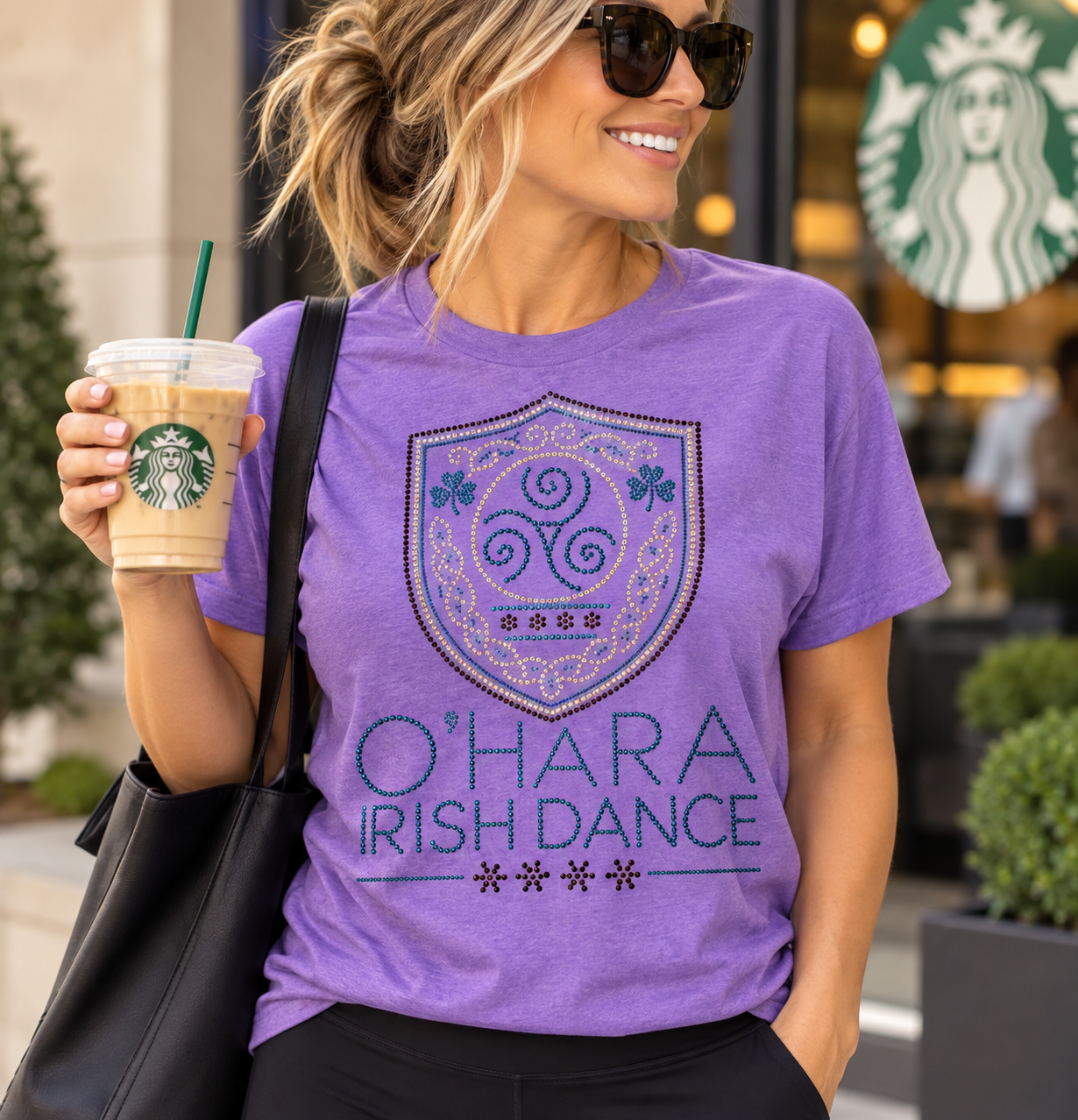 Woman wearing the O'Hara Irish Dance rhinestone t-shirt in heather purple with a purple, AB and aqua rhinestone crest logo