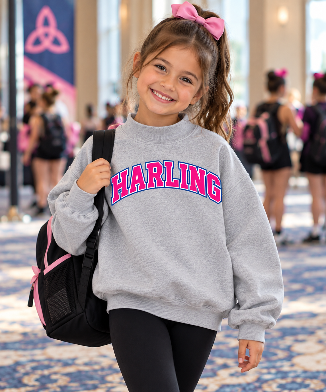 Smiling young Irish dancer with a pink bow wearing the Harling mockneck sweatshirt