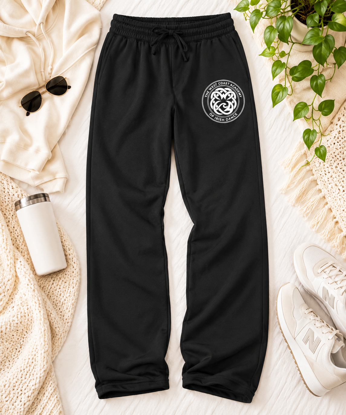 West Coast Academy black sweatpants with the white school crest on the upper thigh, flat lay